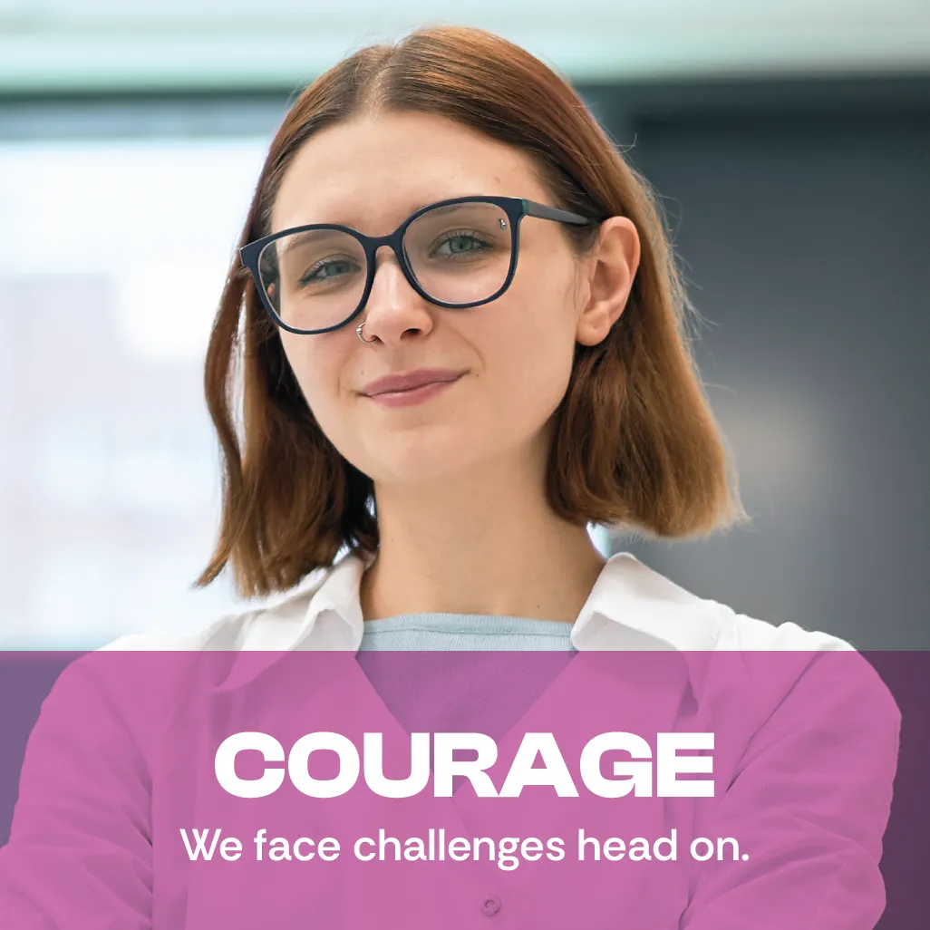Courage. We face challenges head on.  A photo of a young woman staring straight at you with a facial expression of confidence.