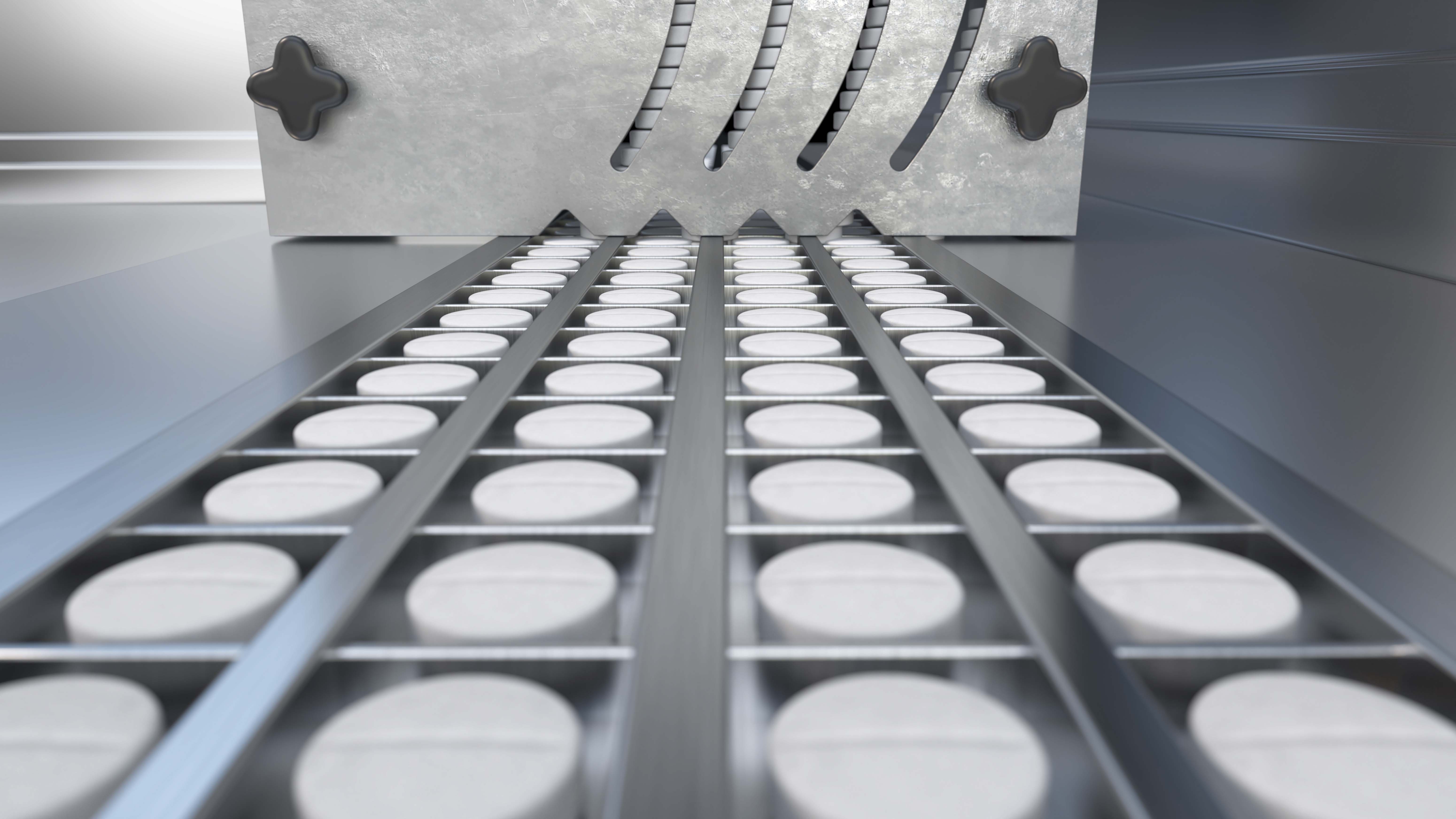 White, circular pills on a conveyor belt
