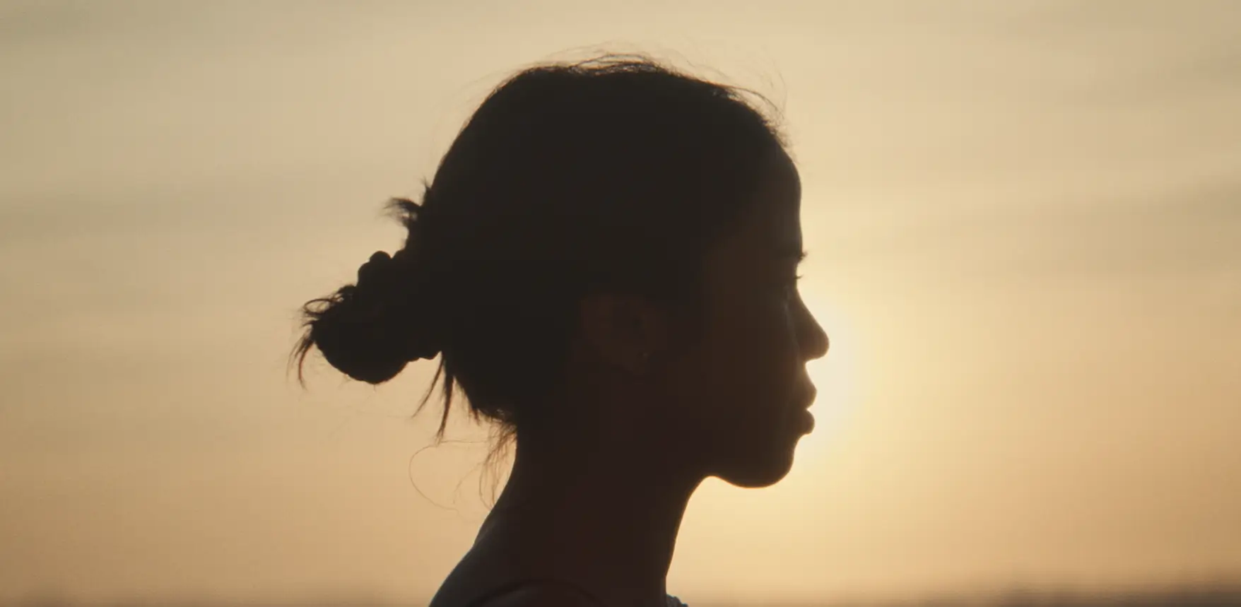 Silhouette d’une femme de profil devant un ciel au coucher du soleil