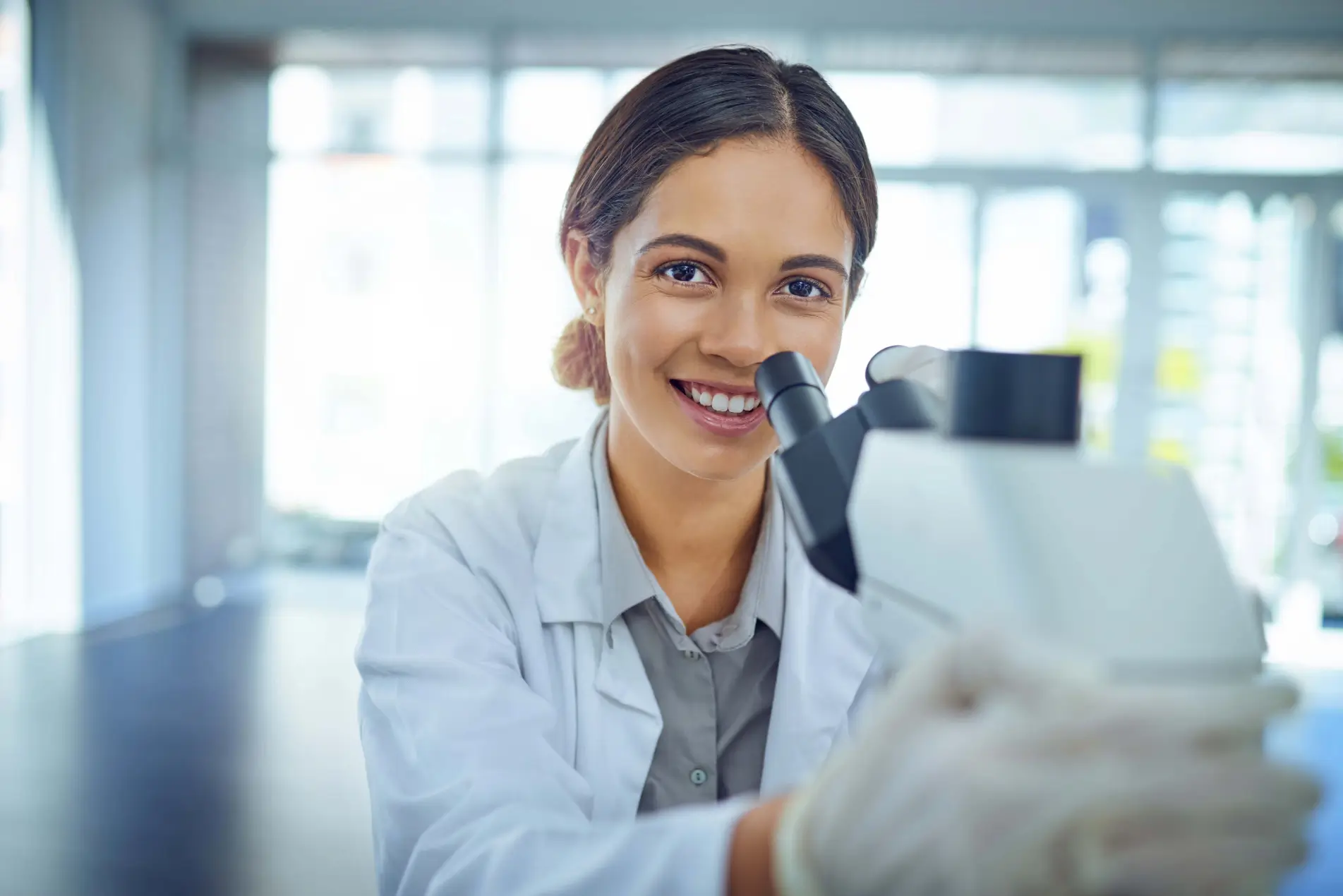 Científico sonriente utilizando un microscopio.