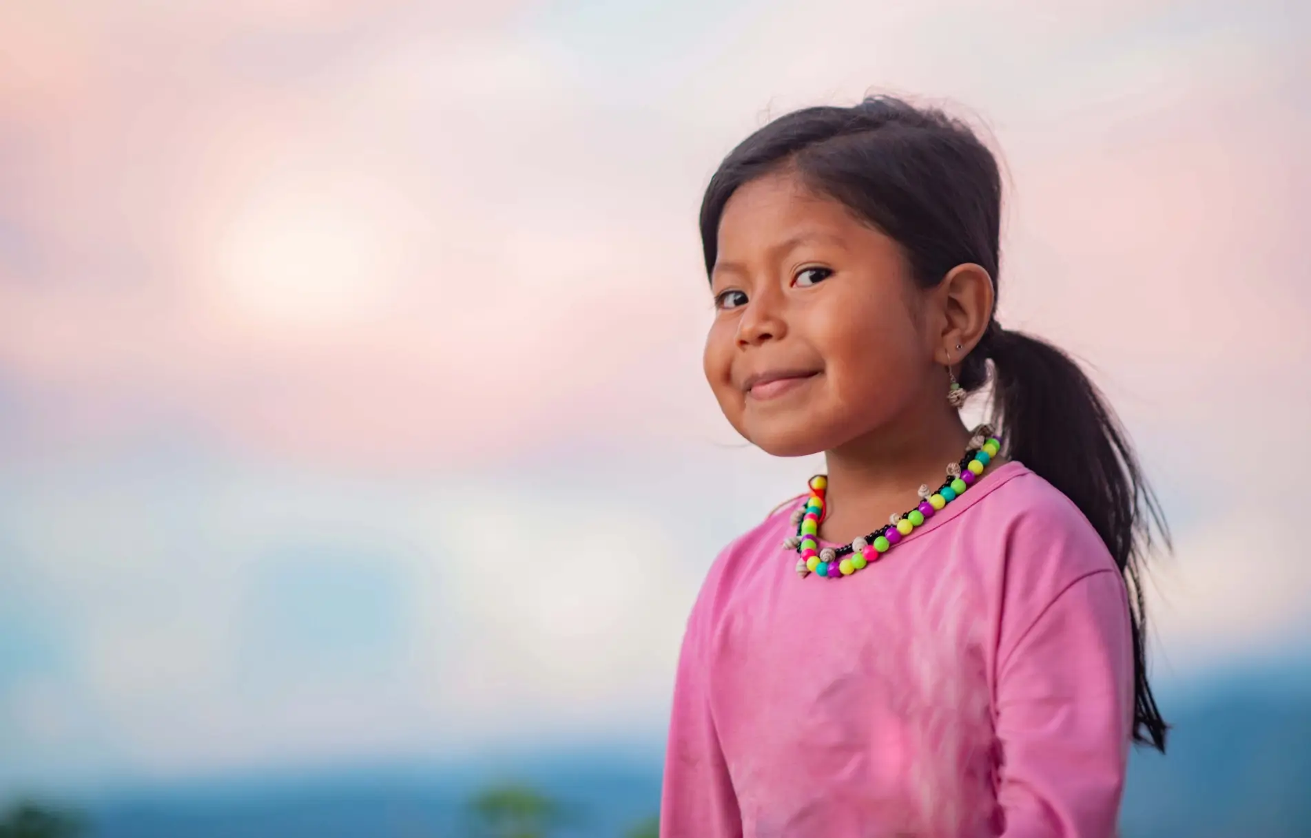 Una joven con un collar colorido sonriendo a la cámara.