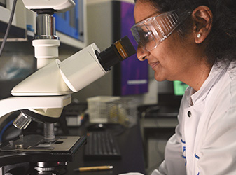 Woman looking into microscope امرأة تبحث في المجهر